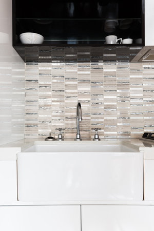 Close up of a deep white kitchen sink and feature tiled splashbackの写真素材