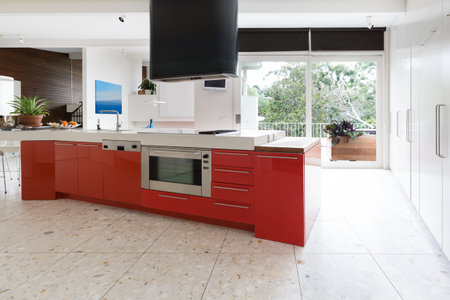 Orange red kitchen cabinets in island bench in modern luxury Australian homeの写真素材