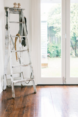 Vintage decor collection of an old ladder, farm bell and rope light in a contemporary homeの写真素材