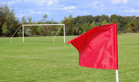A soccer field with a goal and a red flag