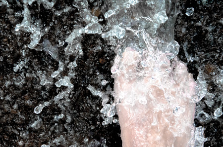A right foot has walking past splash water in the dark ground.の写真素材