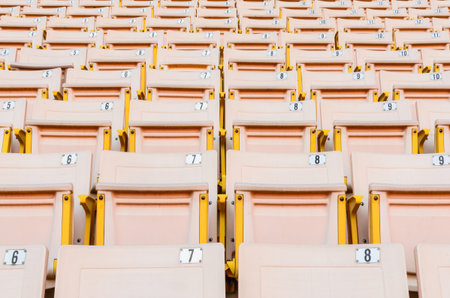 A lot of Light Orange Seat at football stadium in the morning.