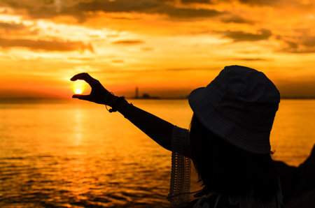 A girl has catching the sun under the sunset sky.の写真素材