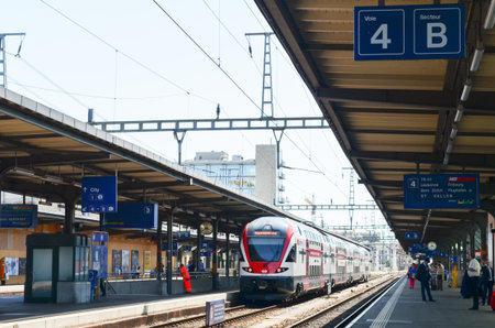 Editorial: Switzerland, 14th July 2012. People waiting train at station, business and lifestyle with building and city.のeditorial素材