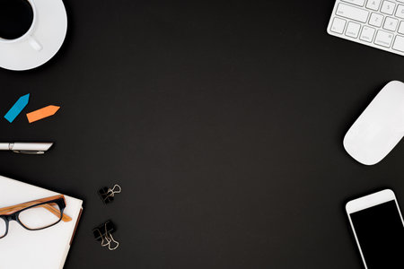 Office desk table with computer, eyeglass, white mouse, silver pen, multi color sticky note and black coffee cup. Business desk table top view with copy space concept.の写真素材