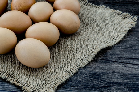 A lot of brown chicken eggs on the brown wooden table background.