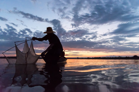 Silhouette of Fishermen throwing net fishing in sunset time at Wanon Niwat district Sakon Nakhon Northeast Thailand.の写真素材