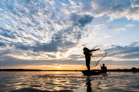 Silhouette of Fishermen throwing net fishing in sunset time at Wanon Niwat district Sakon Nakhon...