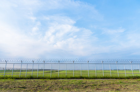 Rusty barbed wire fence under the blue sky in the morning.