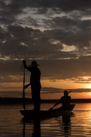 Silhouette of Fishermen throwing net fishing in sunset time at Wanon Niwat district Sakon Nakhon Northeast Thailand.の写真素材