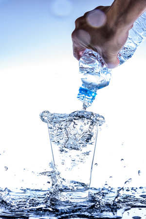 Pouring water and splashing in the glass with reflection on mirror.の写真素材