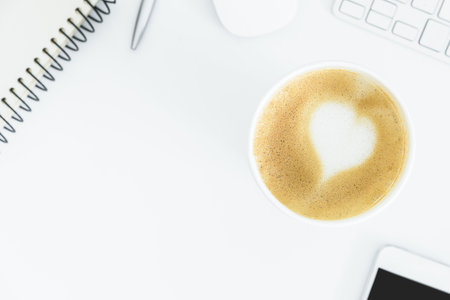 A latte coffee with art heart milk on the white desk table from top view and copy space. Flat lay with desk, business and valentine concept.の写真素材