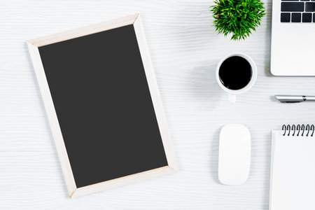 White wood office desk table and equipment for working with black coffee and blank board in top view and flat ray concept.の写真素材