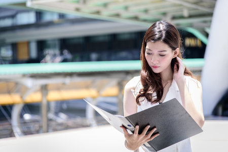 The asian business woman working and operation in outside office with building and city background.の写真素材