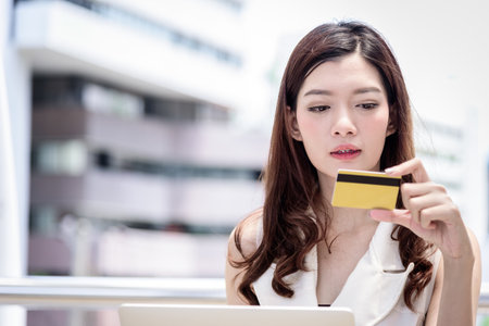 The asian business woman has shopping and buying with credit card from outside office with building and city background.の写真素材
