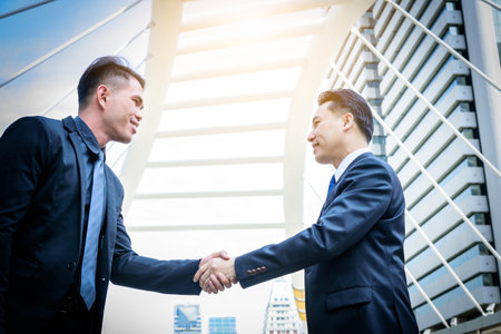 Two asian business have handshake with building and city background.の写真素材
