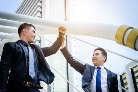 Two asian business have victory of business goal with building and city background.の写真素材