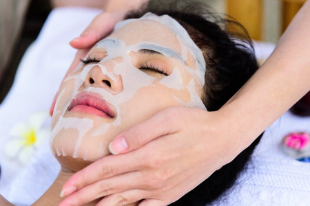 Portrait of beautiful asian people has masking with close up view and close up eyes and having hand massage in spa salon. Beauty, healthy, spa and relaxation concept.の写真素材