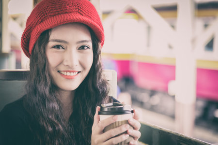 Asian woman traveler has drinking a cup of coffee with traveling by train at Hua Lamphong station at...
