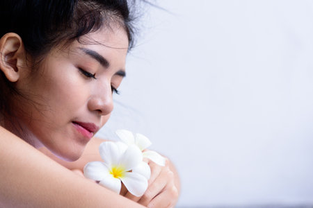 Portrait of beautiful asian people with close up view and close up eyes and smelling a flower. Beauty, healthy, spa and relaxation concept.の写真素材
