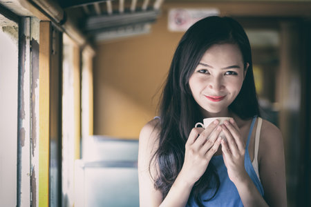 Asian woman traveler has drinking coffee in the train with happiness at Hua Lamphong station at Bangkok, Thailand.の写真素材