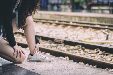 Asian woman traveler has tying shoe laces for traveling by train at Hua Lamphong station at Bangkok, Thailand.の写真素材