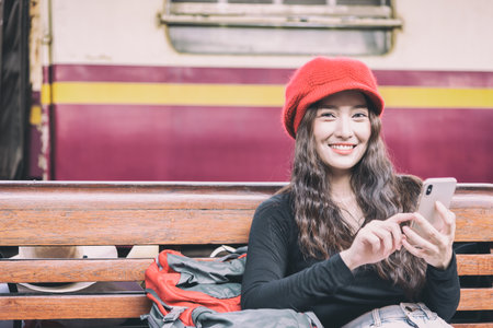 Asian woman traveler has playing with phone and waiting the train at Hua Lamphong station at Bangkok, Thailand.の写真素材