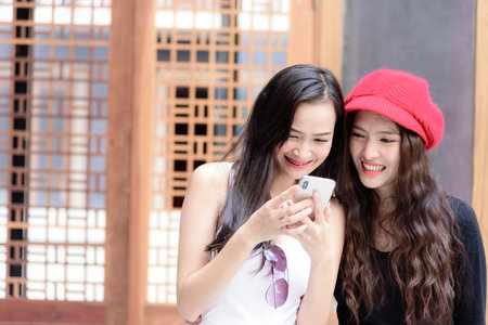 Asian women traveler have playing a mobile phone and talking with fun and happiness.の写真素材