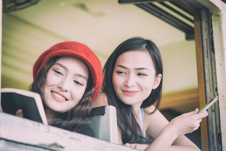 Asian women traveler have reading a book and talking in the train with happiness at Hua Lamphong station at Bangkok, Thailand.の写真素材