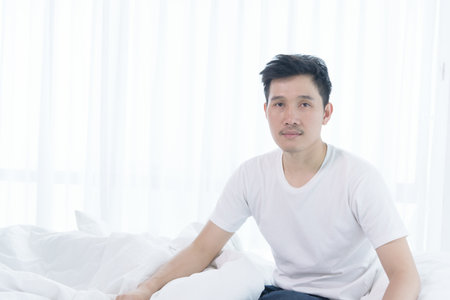 Asian man has wake up with lazying on bed in the morning.の写真素材