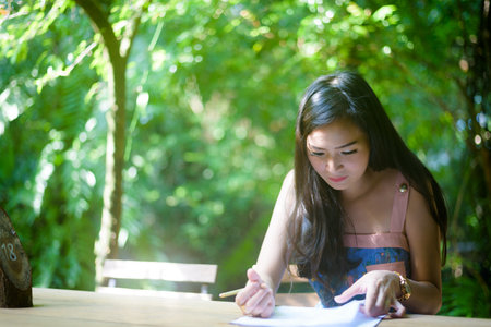 Asian pretty girl has writing order with happy and smiling at Little Tree Garden cafe, Nakhon Pathom province, Thailand in the morning.の写真素材