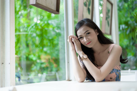 Asian pretty girl has relaxing with happy and smiling at Little Tree Garden cafe, Nakhon Pathom province, Thailand in the morning.の写真素材