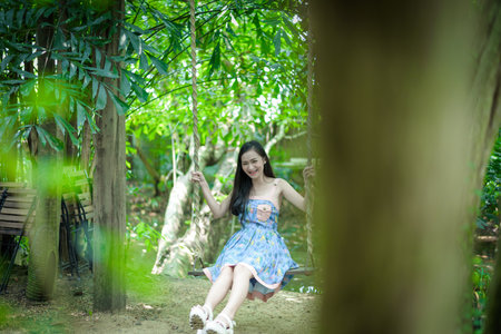 Asian pretty girl has relaxing with swing at Little Tree Garden cafe, Nakhon Pathom province, Thailand in the morning.の写真素材