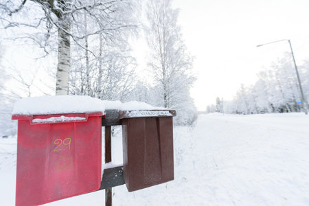 The red and brown mailbox has covered with heavy snow in winter season at Lapland, Finland.