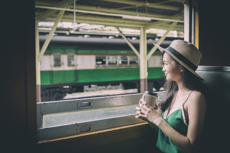 Asian woman traveler has drinking coffee in the train with happiness at Hua Lamphong station at...