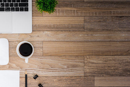 The office desk flat lay view with laptop, mouse, tree, black clip, coffee cup, notebook, pencil on...