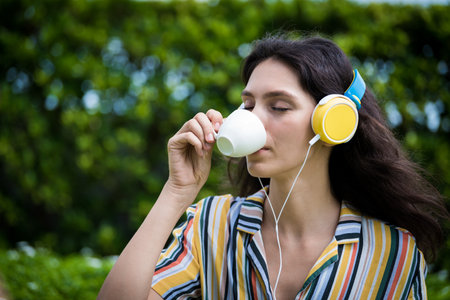 Portrait of a beautiful woman has drunk a coffee and listening to music with smiling and relax in the garden.の写真素材