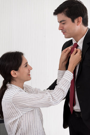 Wife tying red necktie to her husband in the office with smiling and happy.の写真素材