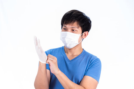 Asian young man in blue t-shirt top with medical mask and latex gloves to protect COVID-19 with isolated on white background concept.の写真素材