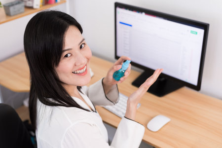 A beautiful Asian businesswoman cleaning hands by cleaner gel to protect COVID-19 before start...