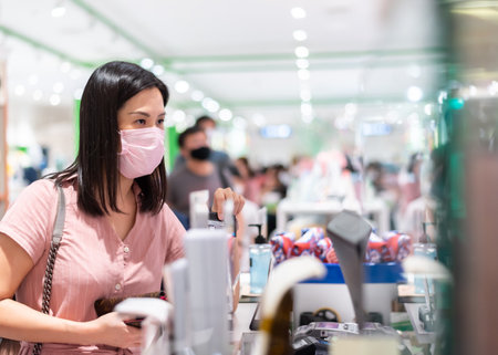 An Asian woman paid with credit card in the shopping mall after opening lockdown with pink mask and social distancing.の写真素材