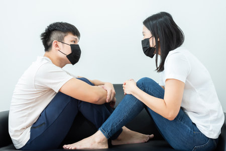 An Asian couple wearing a black mask and stays together with boring and social distancing.の写真素材