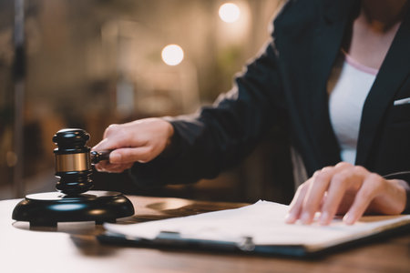 The gavel blow of a judge or decision-maker to authority about business, justice, or the law for a court proceeding. A picture of a hand hitting a hammer for finalizing the decision in courtroom.の写真素材