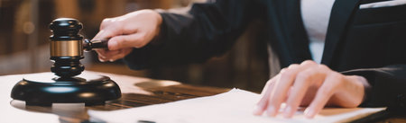 Banner background of A picture of a hand hitting a hammer. The gavel blow of a judge or decision-maker to authority about business, justice, or the law for a court proceeding.の写真素材