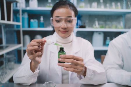 Researcher woman are drop a liquid to a bottle in her hand and researcher man are look to substance and note to notebook in his hand at laboratory.の写真素材