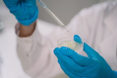 Chemist drop fluid of a bottle in the product research laboratory. Scientist researcher dosing and...