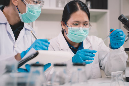 A food scientist looks at a milk sample of a product in a lab. 2 Researchers are studying and taking notes on milk.の写真素材