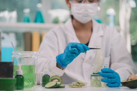 A reseracher using a tweezers to hold a round slice of fruits in cosmetic lab for beuty. fruits has nutritional value and great health benefitsの写真素材