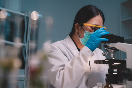 Two scientists looking through a microscope an ecological skin care experiment in a night lab development concept. Research with plants and scientific extraction in glassware. Green alternative herbal medicine for physical health careの写真素材