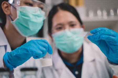 Food scientist or two researcher testing milk samples of dairy products in the laboratory. Researchers are looking and compare milk.の写真素材